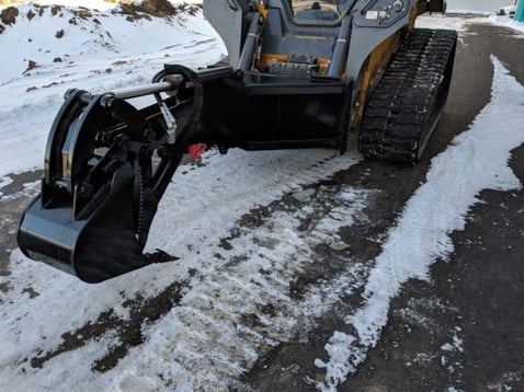 A backhoe attachment excavating during winter